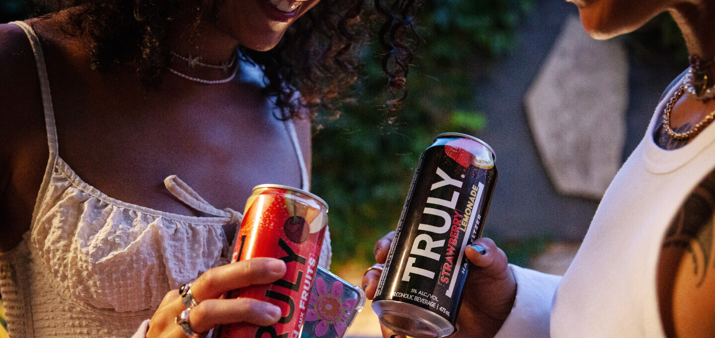 Two girls holding Truly cans.